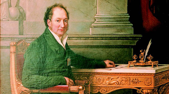 Kurfürst Maximilian I. Joseph von Bayern (1756-1825) sitzt an einem Schreibtisch, auf dem ein Blatt liegt und eine Schreibtischgarnitur mit einer kleinen Figur steht. 